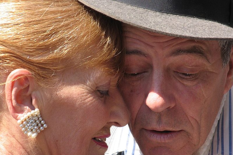 A tango couple dancing cheek to cheek in a close embrace